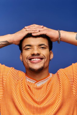 Turuncu çizgili gömlekli yakışıklı adam neşeli bir hareketle mutluluğu ifade ediyor..