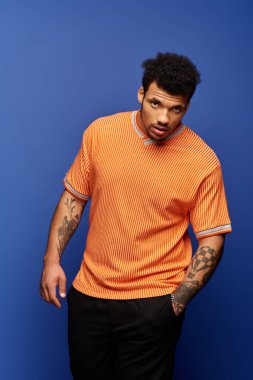 Şık bir adam kendine güvenen yüz ifadesiyle eşsiz moda anlayışını kapalı mekanda sergiliyor..