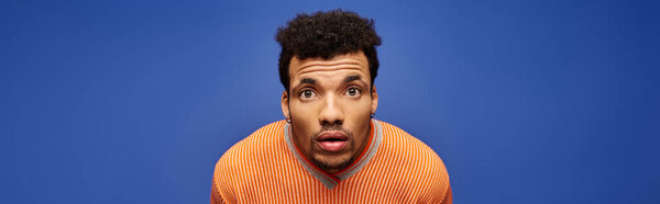 Красивый мужчина задумчиво позирует на ярко-голубом фоне, излучающем очарование..