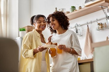 Güneşli bir sabahta iki genç kadın modern dairelerinde kahkaha ve kahvaltıyı paylaşıyor..