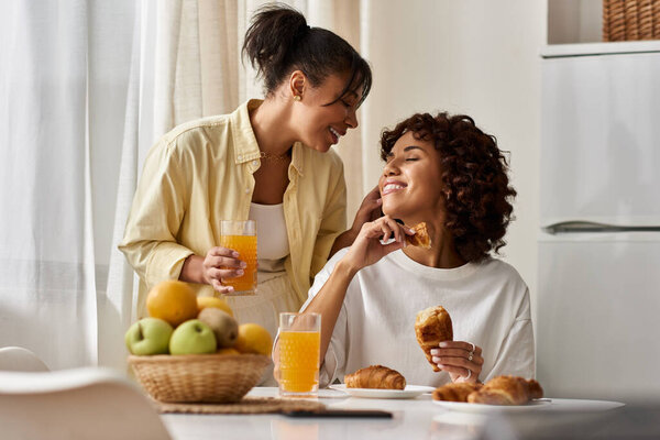 Две счастливые женщины наслаждаются завтраком вместе, разделяя смех и любовь в их стильном доме.