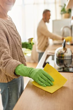 A mature couple shares a joyful moment as they clean their home, showcasing teamwork and love. clipart