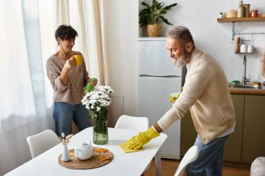 Neşeli, olgun bir çift, parlak mutfaklarında birlikte temizlik yapmaktan zevk alır..