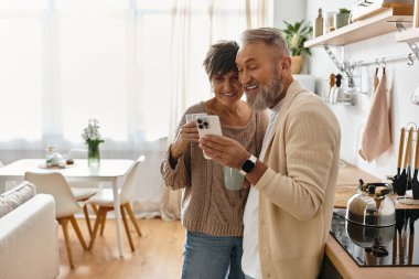 Yetişkin bir çift evde birlikte telefona bakarken keyifli bir anın tadını çıkarıyor..