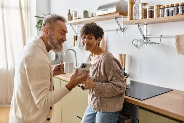 Samimi bir mutfakta telefonlarını kontrol ederken birlikte gülüp gülüyorlar..