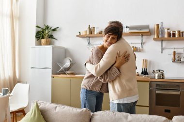 Mutlu, olgun bir çift, parlak mutfaklarında sıcak bir kucaklaşmayı paylaşır..