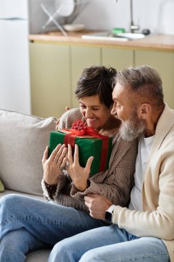 Olgun bir çift, keyifle gülümser. Hoş oturma odalarında güzel bir hediyeyi açarken..