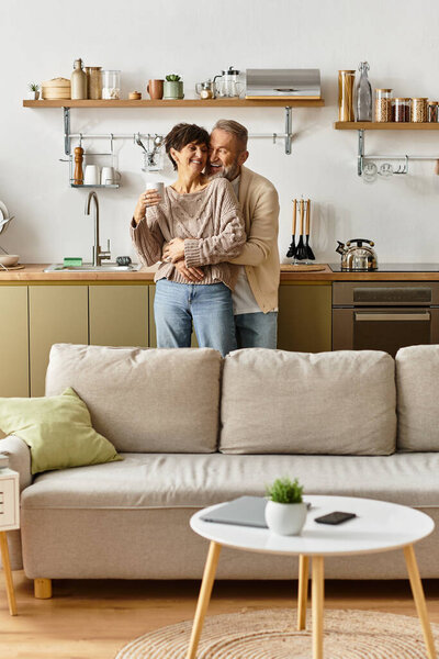 Couple embraces joyfully while preparing a meal in their bright, modern kitchen space.