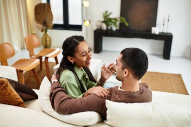 Güzel bir çift, tatil neşesiyle çevrili şık oturma odalarında sıcak bir anı paylaşır..