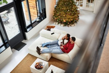 Bir çift, Noel ruhuyla dolu modern bir dairede birlikte vakit geçirmenin keyfini çıkarıyor..