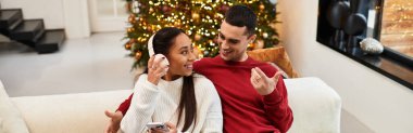 A couple enjoys a delightful moment together in a festive living room adorned for Christmas, banner clipart