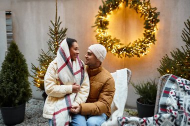 Kışın giyinmiş güzel bir çift Noel ışıklarıyla birlikte dışarıda eğleniyor..