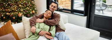 A joyful couple relaxes in their modern living room, surrounded by festive decorations and love, banner clipart