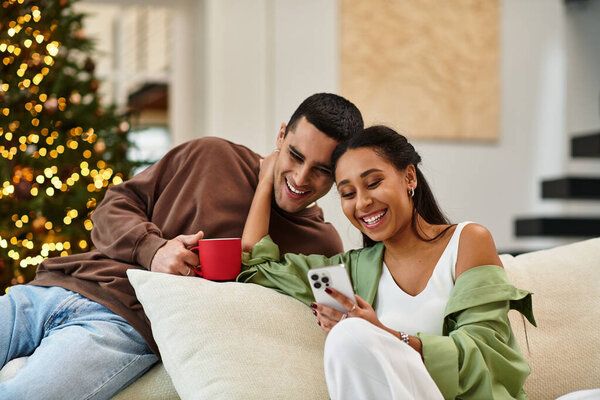 A couple shares laughter and warmth in a stylish living room filled with Christmas cheer.