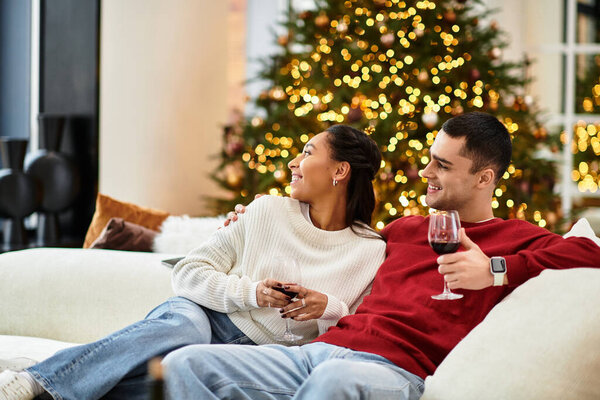 A couple enjoys each other's company, sipping drinks in a beautifully decorated living room.