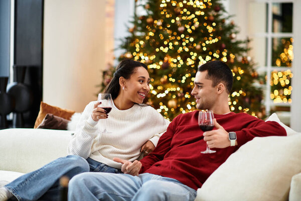 Couple relaxes happily in their modern living room, sharing drinks and festive cheer.
