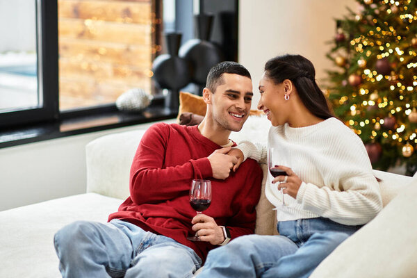 Couple enjoys each others company over drinks in a beautifully decorated living room for Christmas.