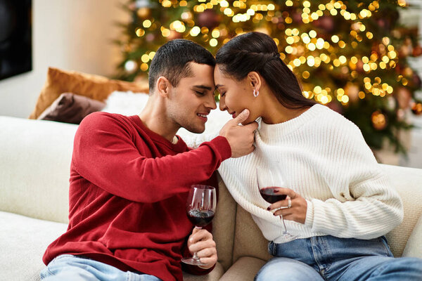 A loving couple shares a tender moment while enjoying wine in a beautifully decorated apartment.