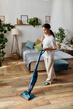 A young African American woman thoughtfully cleans her modern apartment while tidying up. clipart