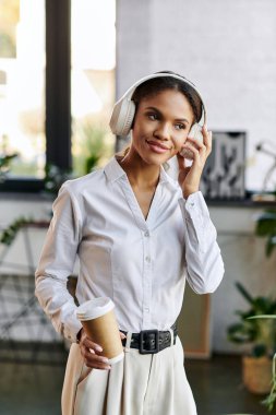 Modern bir ofiste, genç bir Afrikalı Amerikalı iş kadını çalışırken müzik dinler..