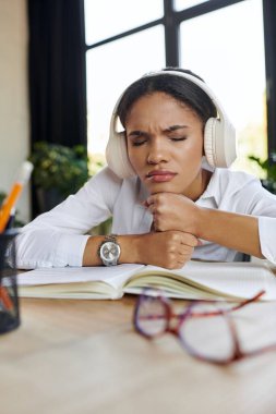 Young professional wearing headphones in a stylish workspace, listening music clipart