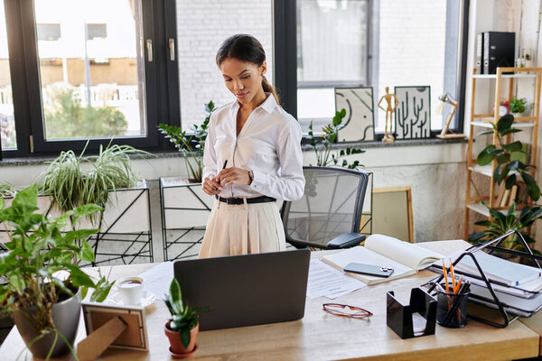 Сфокусированная молодая афроамериканка в белой рубашке усердно работает в современном офисе.