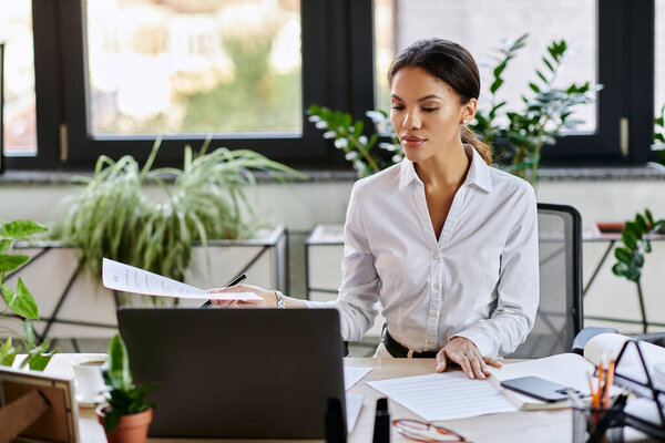 Профессиональная деловая женщина в белой рубашке рассматривает документы за рабочим столом.