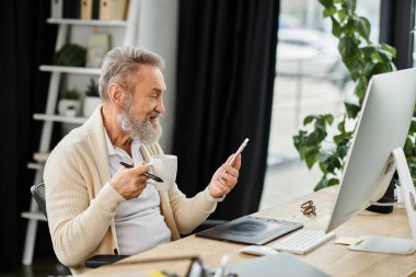 Yakışıklı son sınıf öğrencisi kahveyle rahatlıyor ve akıllı telefonunu parlak bir çalışma alanında kullanıyor..