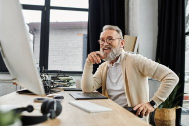 Yakışıklı kıdemli adam, öğleden sonra güneşi altında masasında çalışırken gülümser..