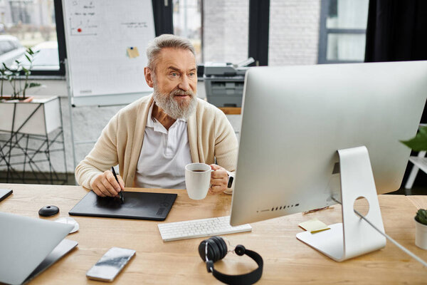 Handsome mature man focused on his work at a stylish desk with coffee and technology.