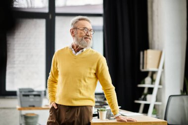 Yakışıklı kıdemli beyefendi şık bir ofiste duruyor, sakinlik ve güven saçıyor..