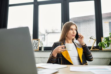 Genç profesyonel masasında raporları incelerken bir telefon görüşmesinde bulundu..