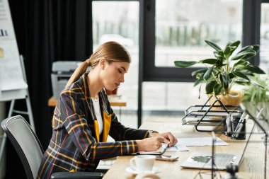 Kareli ceketli şık bir milenyum kadını modern bir ofiste çok çalışır..
