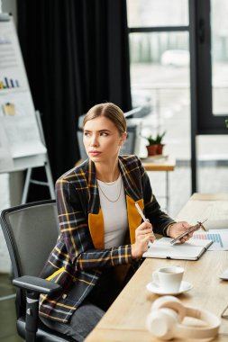 Çekici genç kadın, modern ofis masasında derin düşüncelere dalmıştı. Etrafı gösterişli bir çevreyle çevriliydi..