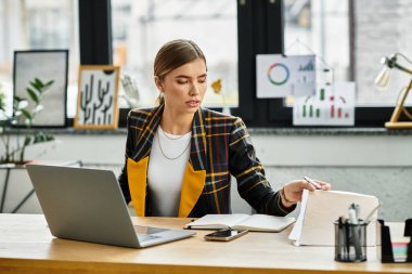 Young woman in a checkered blazer engages with documents while working at her desk.