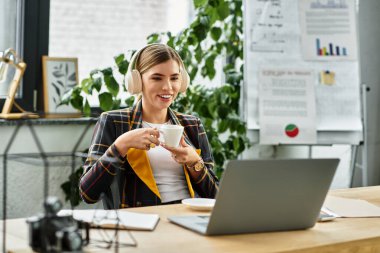 Parlak ofis ortamında, genç profesyonel bir kadın kahvesini yudumlarken kendini işine veriyor..
