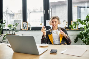 Attractive businesswoman engages in work, sipping tea at her desk in a stylish office setting.