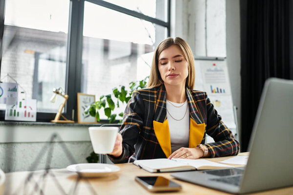 Привлекательная деловая женщина в клетчатом пиджаке фокусируется на своей работе, потягивая кофе.