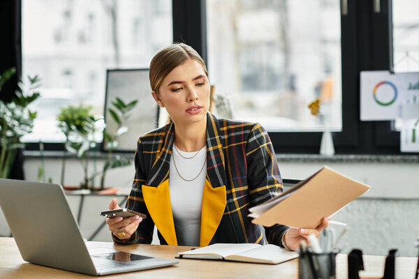 Focused young woman in checkered blazer juggles tasks while working in a bright office space.