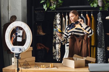 Genç bir kadın moda kıyafetlerini keşfediyor ve moda anlayışını akıllı telefonuyla kaydediyor..