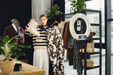 Çekici bir kadın moda seçimlerini sergiliyor, akıllı telefonuyla kıyafet fikirlerini kaydediyor..