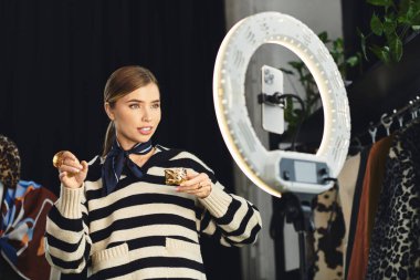 Kendine güvenen genç kadın modaya uygun kıyafetler sergiliyor ve akıllı telefonuyla moda anlayışını paylaşıyor..