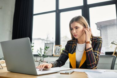 Attractive businesswoman focuses on her tasks while dressed in a stylish checkered blazer. clipart