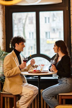 Genç çift, büyüleyici bir restoran ortamında akşam yemeği ve içki eşliğinde özel bir anı paylaşıyor..