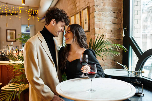 Молодая пара делится романтическим моментом за вином, наслаждаясь Днем Святого Валентина в элегантной обстановке.