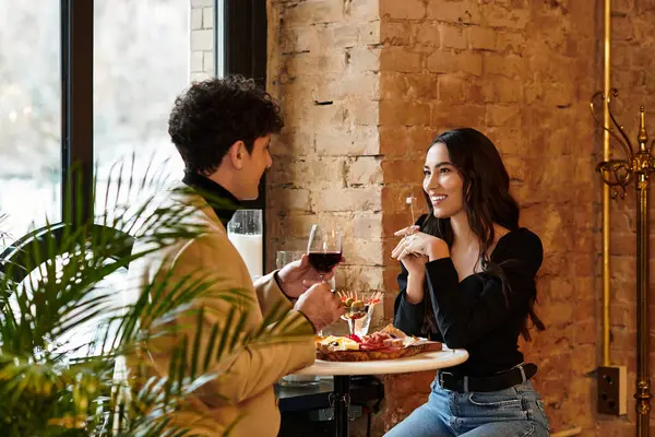 Genç bir çift, samimi bir restoranda romantik bir akşam yemeğinin tadını çıkarıyor..
