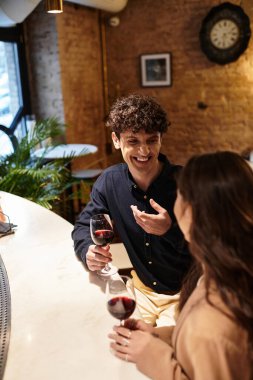 A happy couple enjoys laughter and wine in an intimate restaurant on Valentines Day. clipart