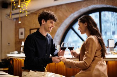 Genç bir çift, aşklarını kadeh kaldırarak ve kahkahalarla kutlayarak samimi bir akşam yemeğinden zevk alır..