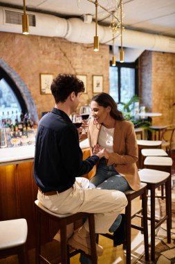 Couple enjoys an intimate moment, sharing laughter and wine at a romantic restaurant celebration. clipart