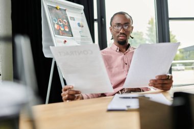 Genç bir Afrikalı Amerikalı, modern bir ofiste çalışırken önemli belgeleri inceliyor..